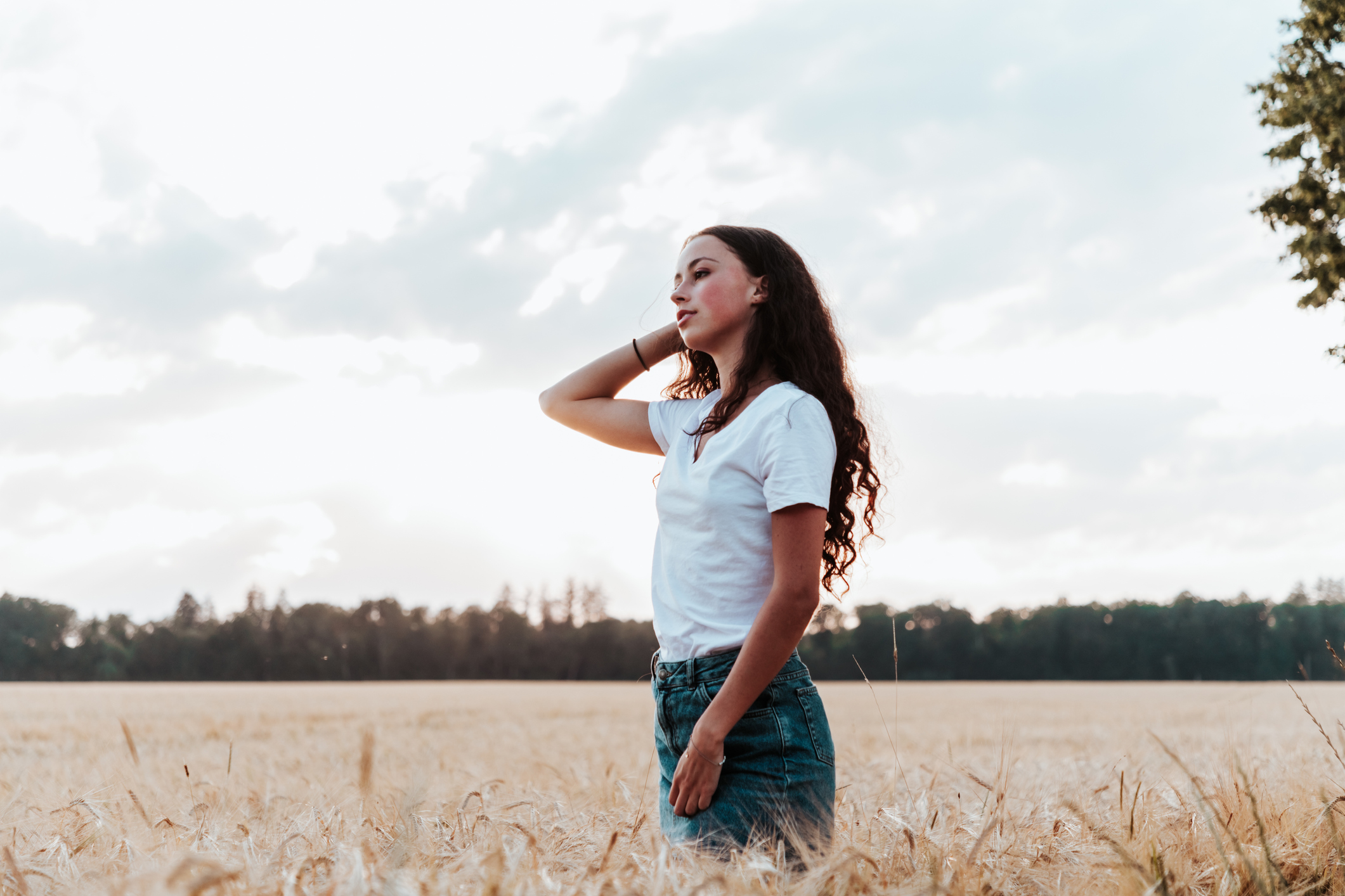 Teenage girl looking to the horizon in summer cornfield, contemplating what to expect on her first gynecologist visit.