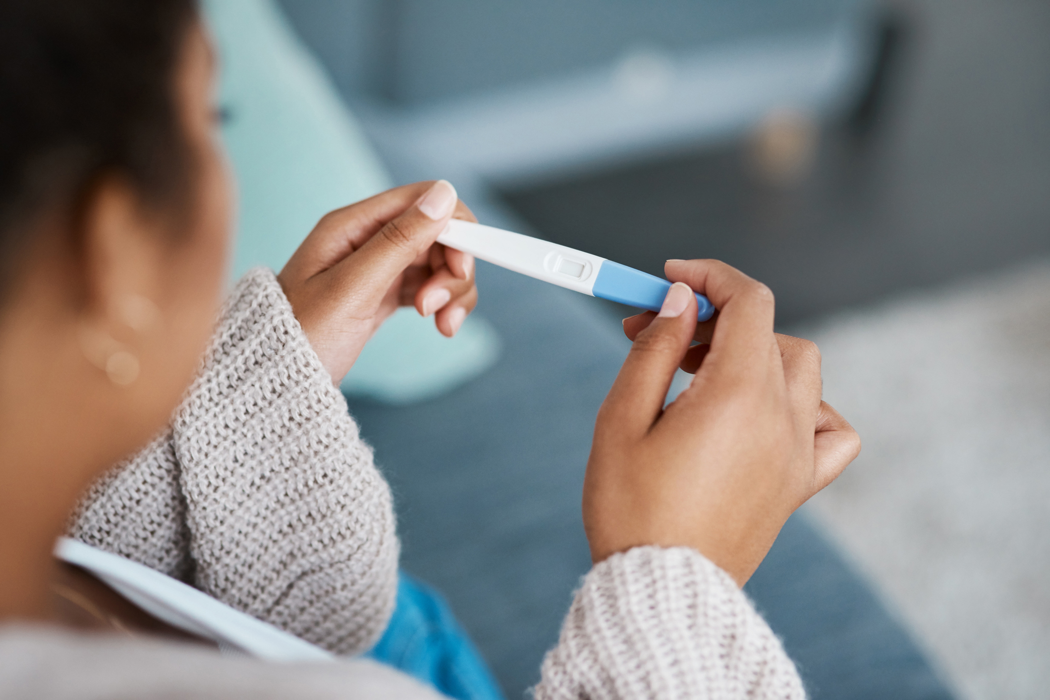 Cropped shot of a woman taking a pregnancy test at home, awaiting fertility discussion with her Ob/Gyn.