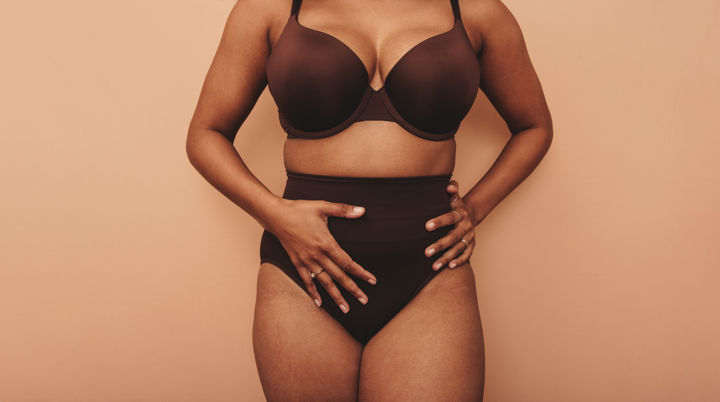 Woman resting hands over vaginoplasty procedure area.