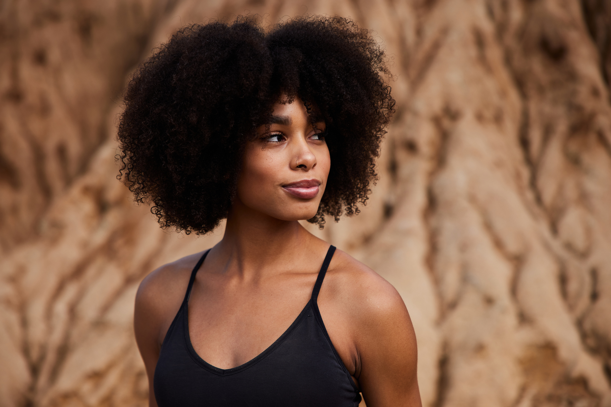 Smiling young African American woman glancing sideways considering what is a labiaplasty.